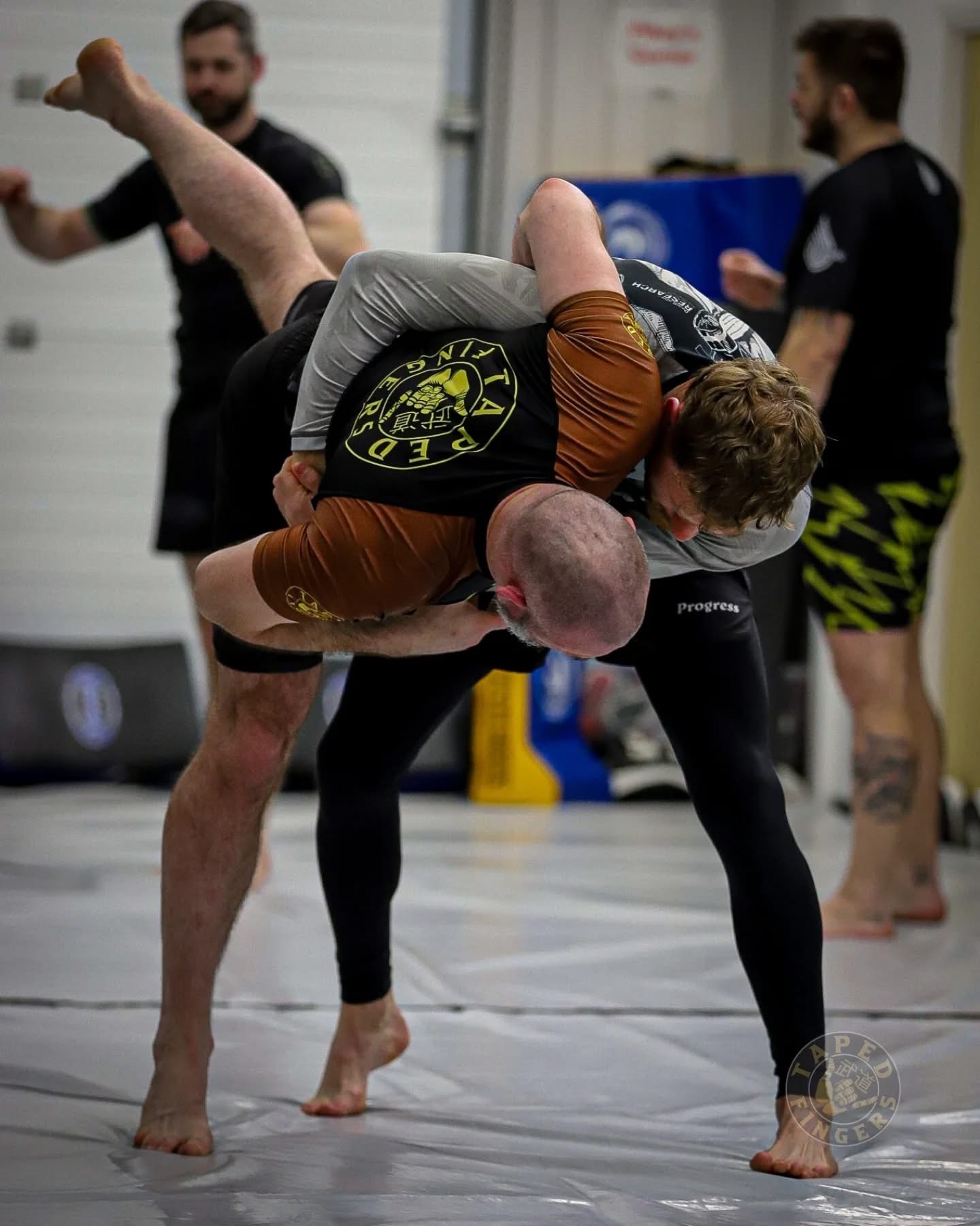 Students training No-Gi grappling on the mats
